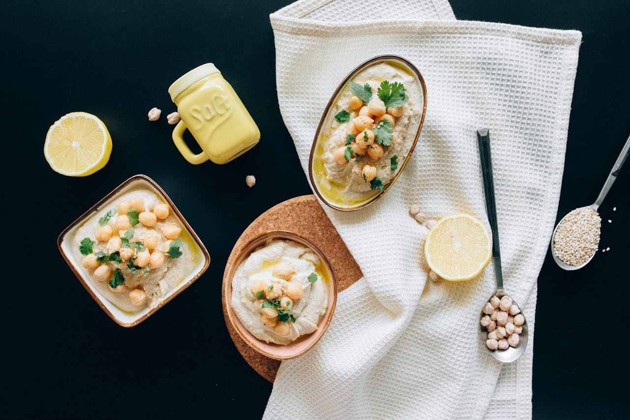 Overhead view of a flavorful Mediterranean hummus spread with garnished chickpeas, lemons, and herbs.